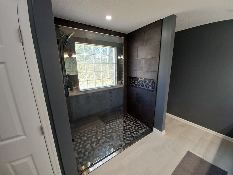 Curbless tile shower with pebble floor and dark accent wall