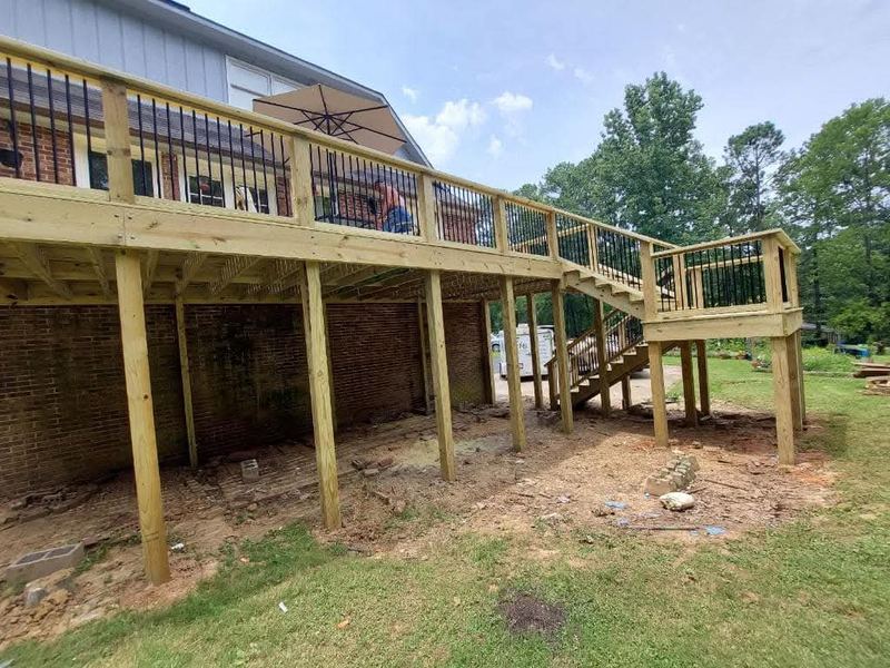 Elevated deck framing with stairs behind a brick home