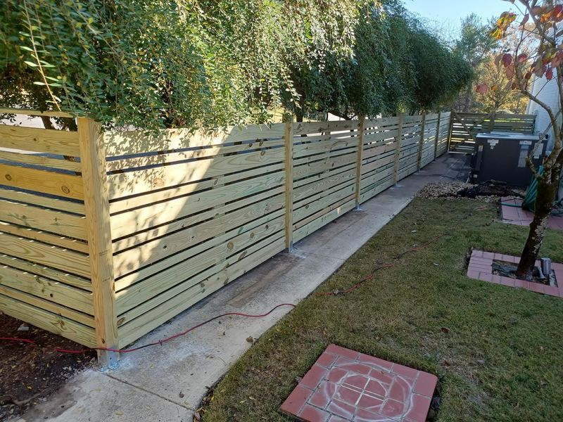 Horizontal slat privacy fence along a back yard