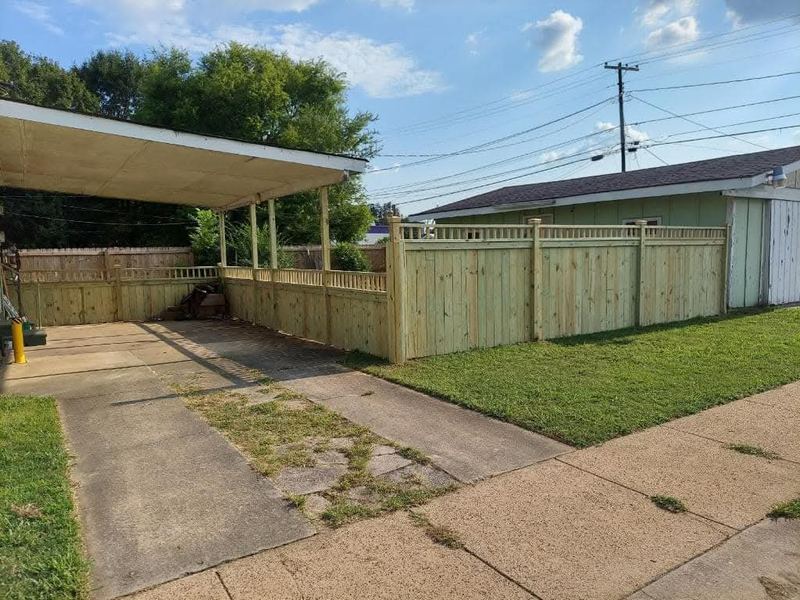 New wood privacy fence along a driveway and carport