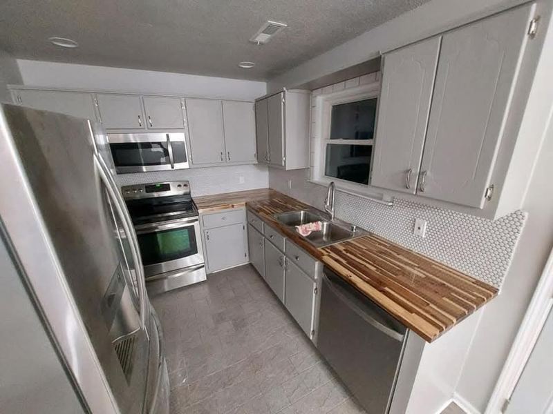 Remodeled kitchen with white cabinets and butcher block counter