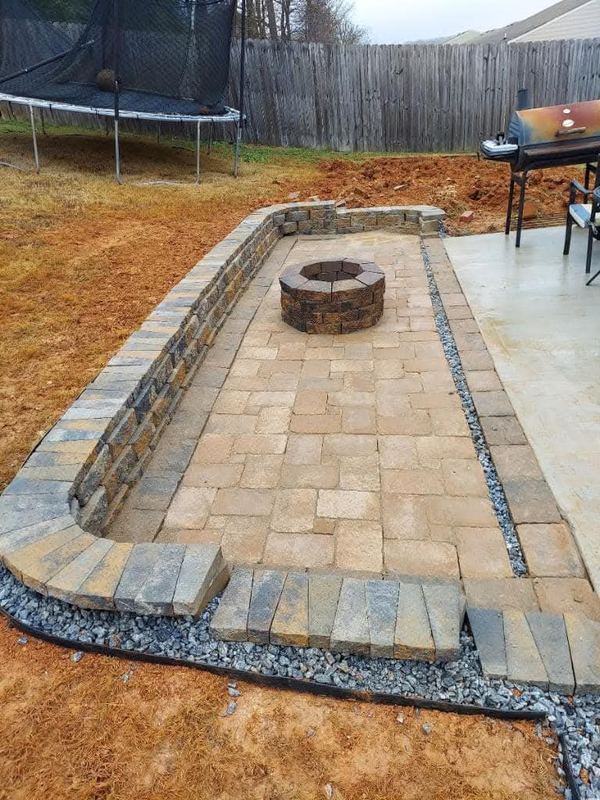 Paver patio with a stone fire pit under construction